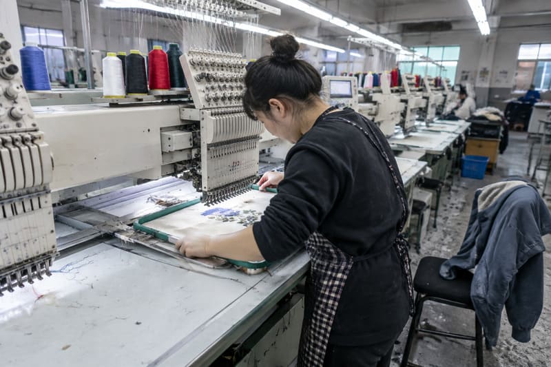 Embroidery machine decorating cut fabric panels in a clothing factory